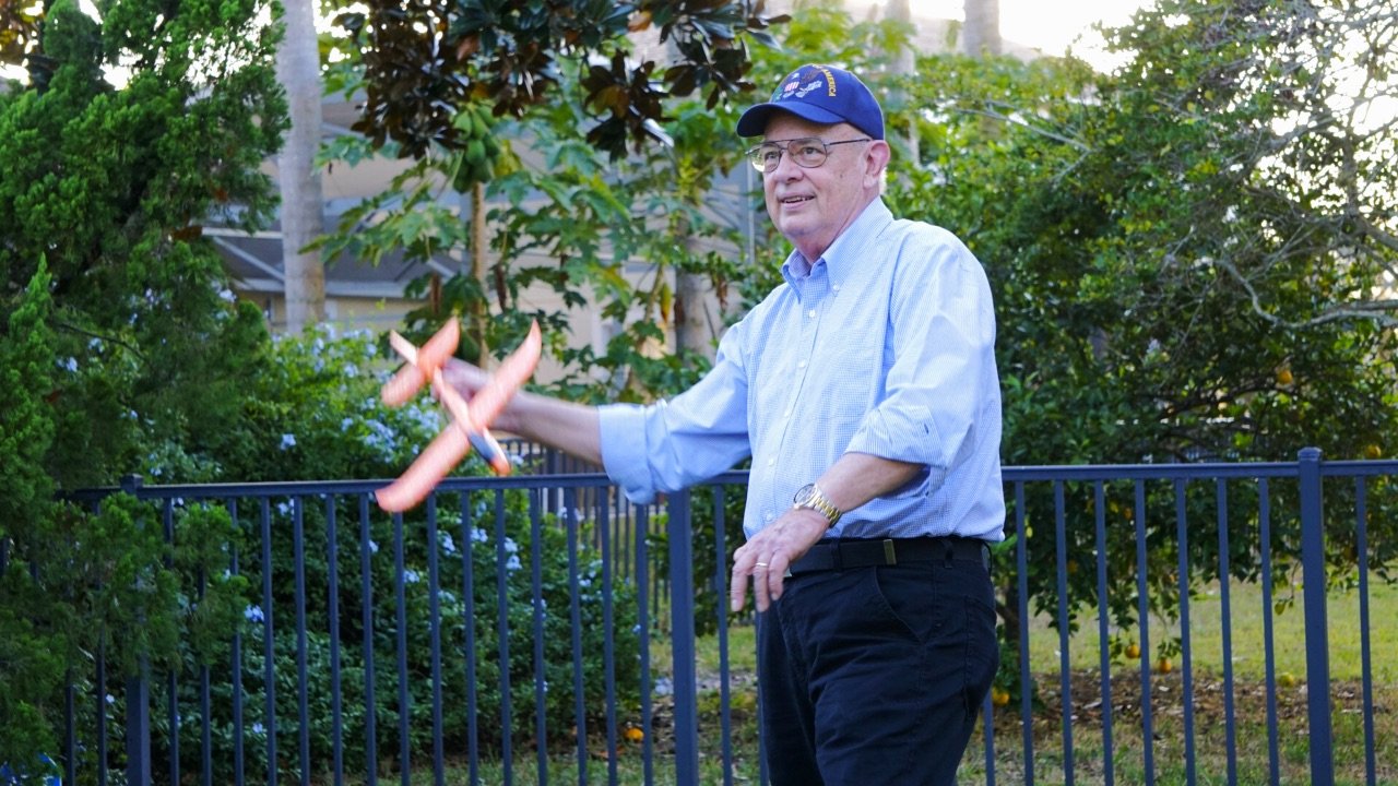 Dan Hopkins smiling and in blue ball cap gets ready to toss a foam glider.