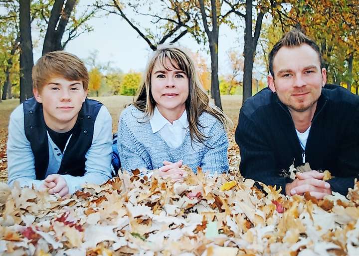 Mom and grown sons posing in Fall portrait.